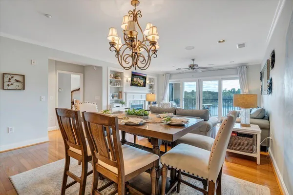 a dining room with wooden floor a chandelier a wooden table and chairs