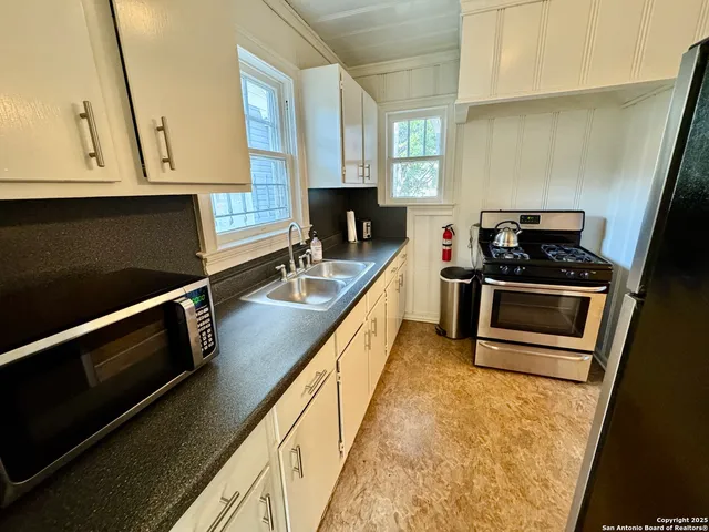 a kitchen with stainless steel appliances a stove a microwave and a sink