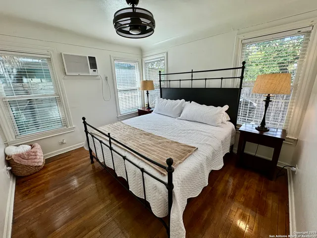 a bedroom with a bed a dresser and wooden floor