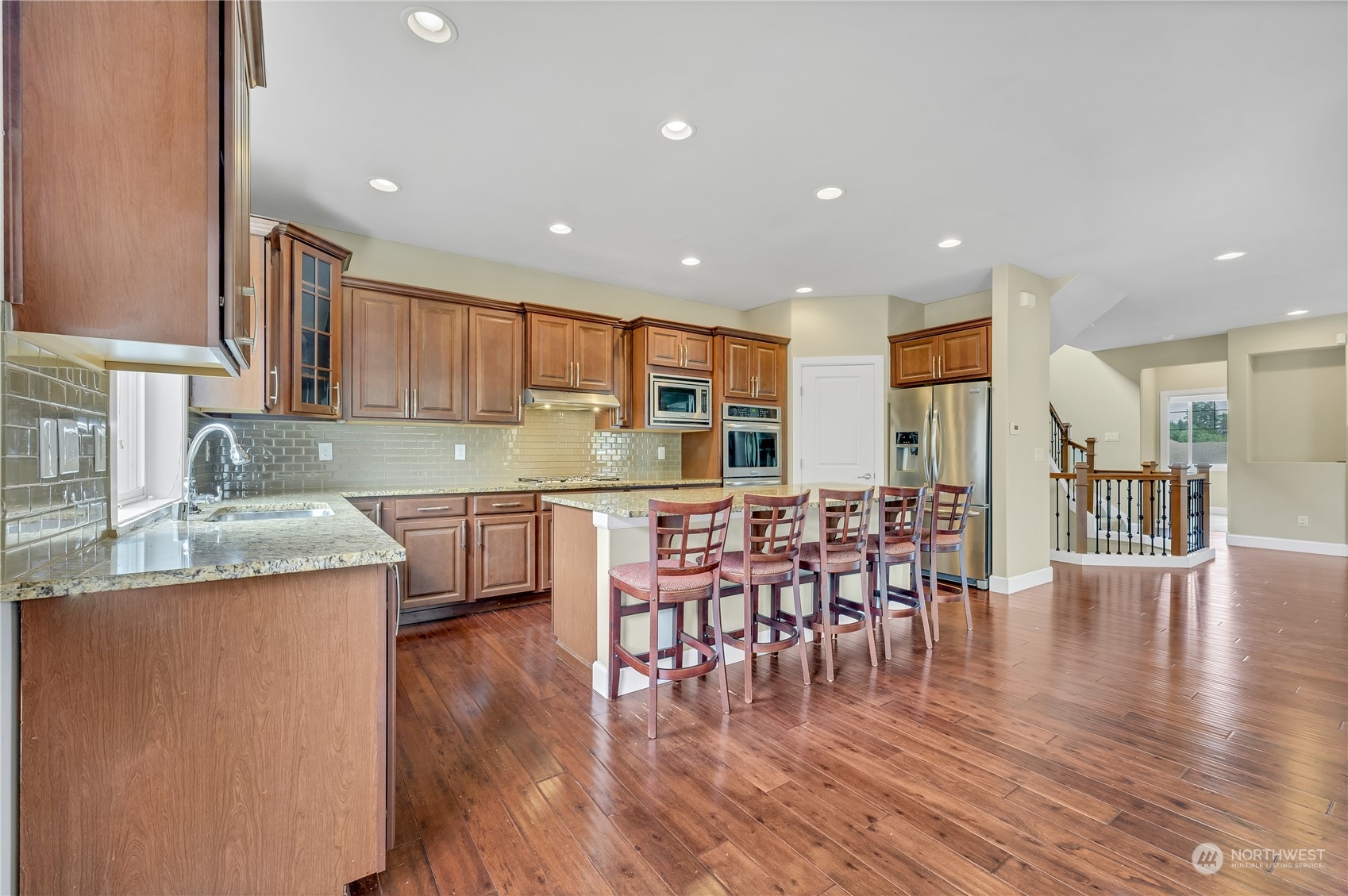 1118 Southwest 338th Street Federal Way, WA 98023 - Photo 10 of 25 a kitchen with stainless steel appliances granite countertop a stove top oven a sink a dining table and chairs with wooden floor