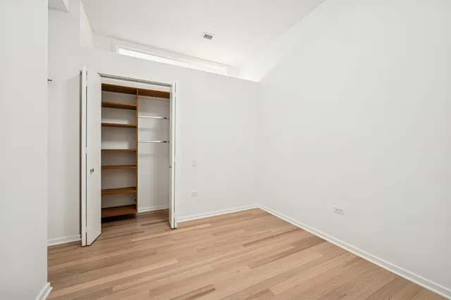 a view of an empty room with wooden floor and closet