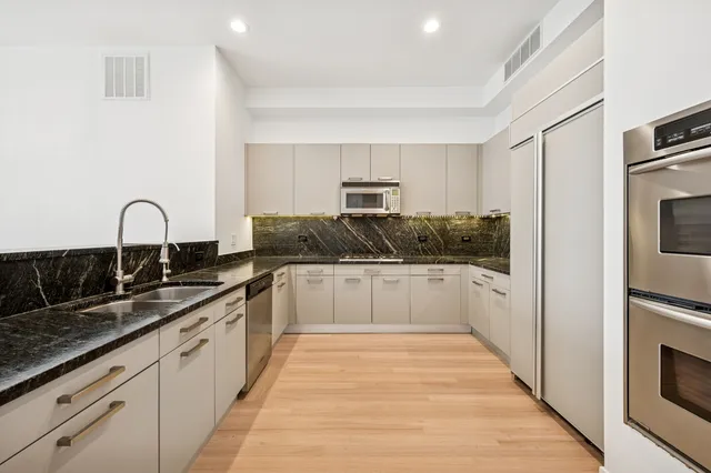 a kitchen with granite countertop white cabinets and stainless steel appliances