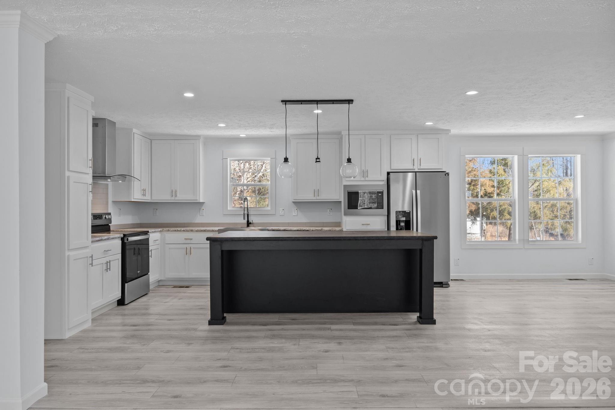 a large kitchen with stainless steel appliances granite countertop a stove a sink and a refrigerator