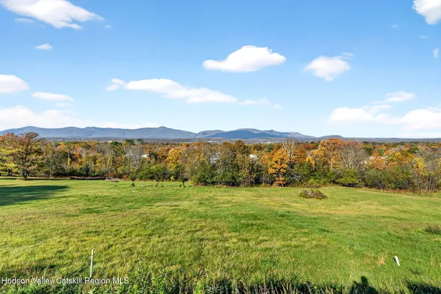 a view of a house with a big yard and large trees