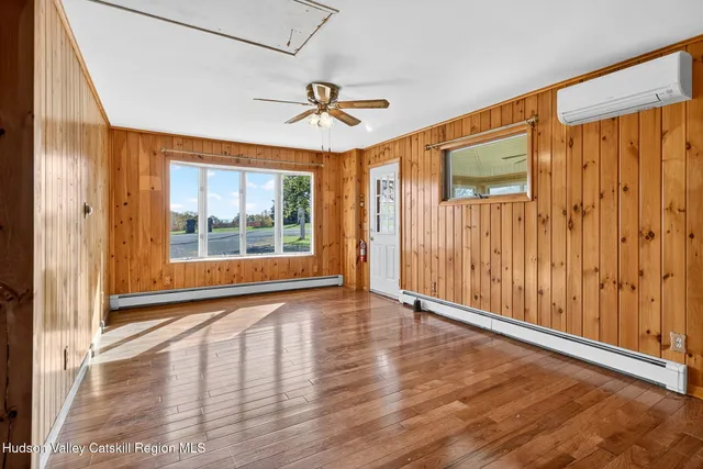a view of an empty room with a window and wooden floor