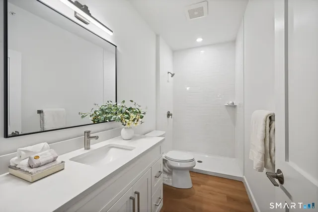 a bathroom with a granite countertop sink a toilet and shower