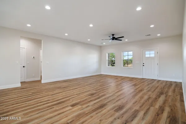 an empty room with wooden floor and windows