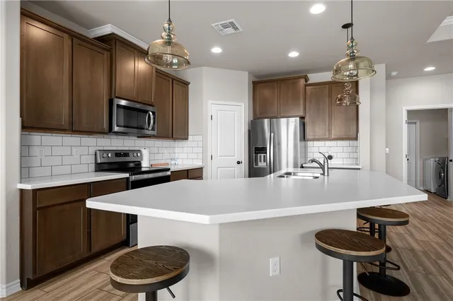 a large kitchen with a dining table chairs wooden floor and a kitchen view