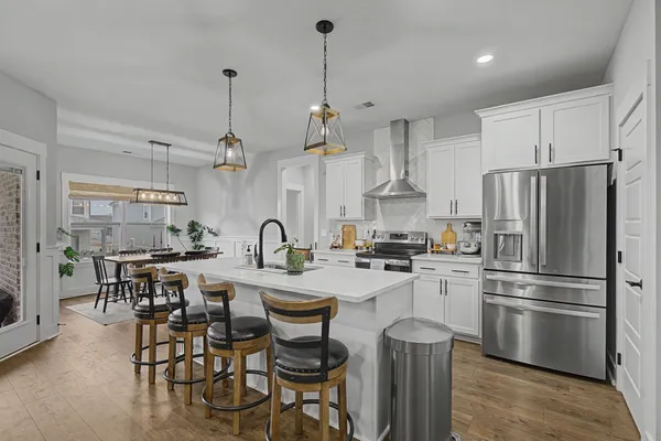 a kitchen with refrigerator a dining table and chairs