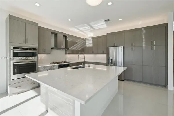 a large kitchen with stainless steel appliances a large counter top a stove a refrigerator and a sink
