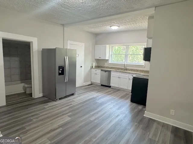 a kitchen with stainless steel appliances granite countertop a refrigerator a sink dishwasher and a stove with wooden floor