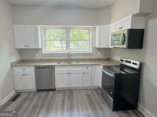 a kitchen with granite countertop cabinets stainless steel appliances a sink and a window