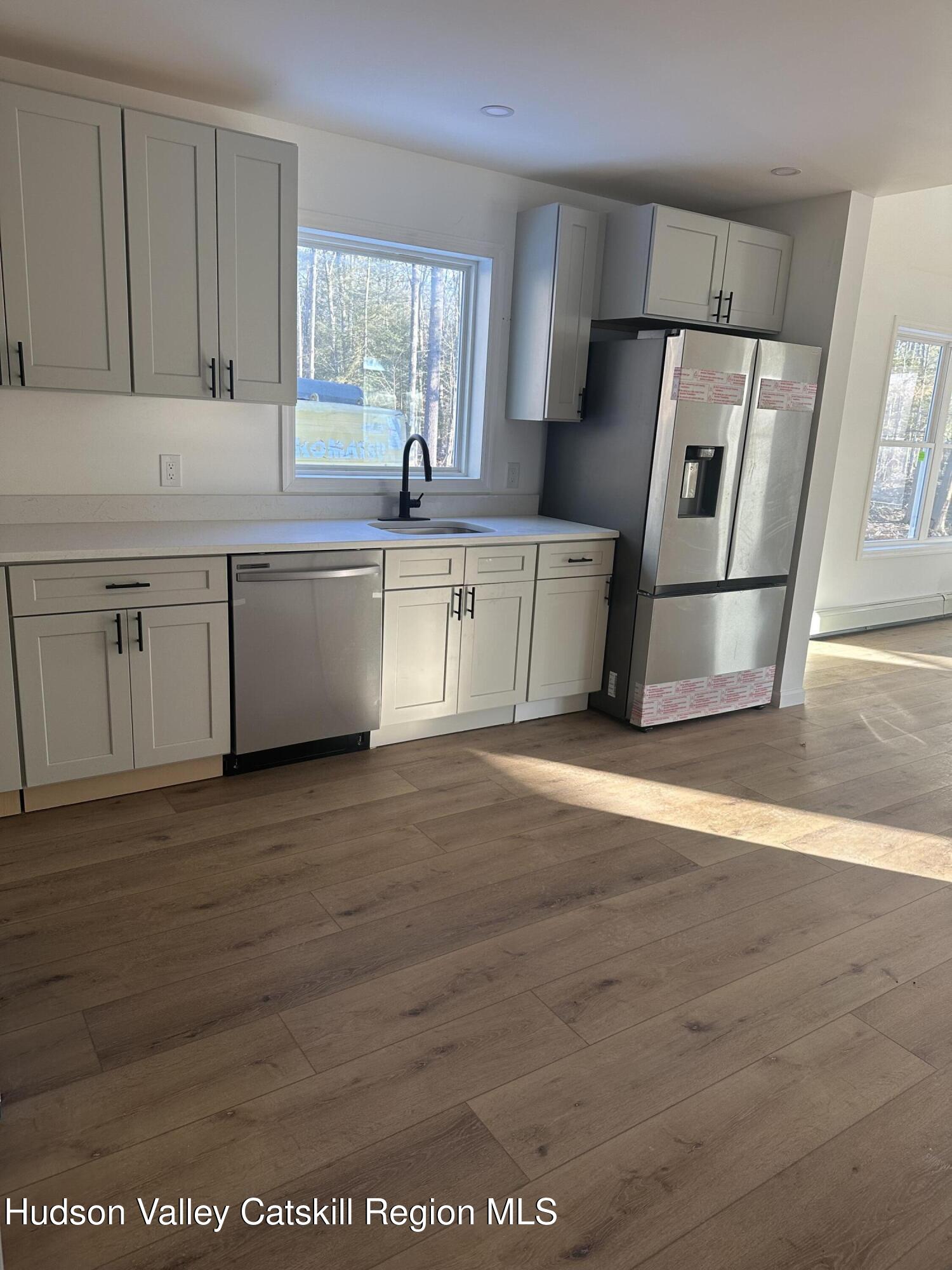 35 Olivers Way Cairo, NY 12413 - Photo 4 of 22 a kitchen with granite countertop a refrigerator a sink dishwasher a stove and white cabinets with wooden floor
