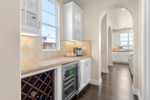 a kitchen with kitchen island granite countertop a white stove top oven and white cabinets with wooden floors