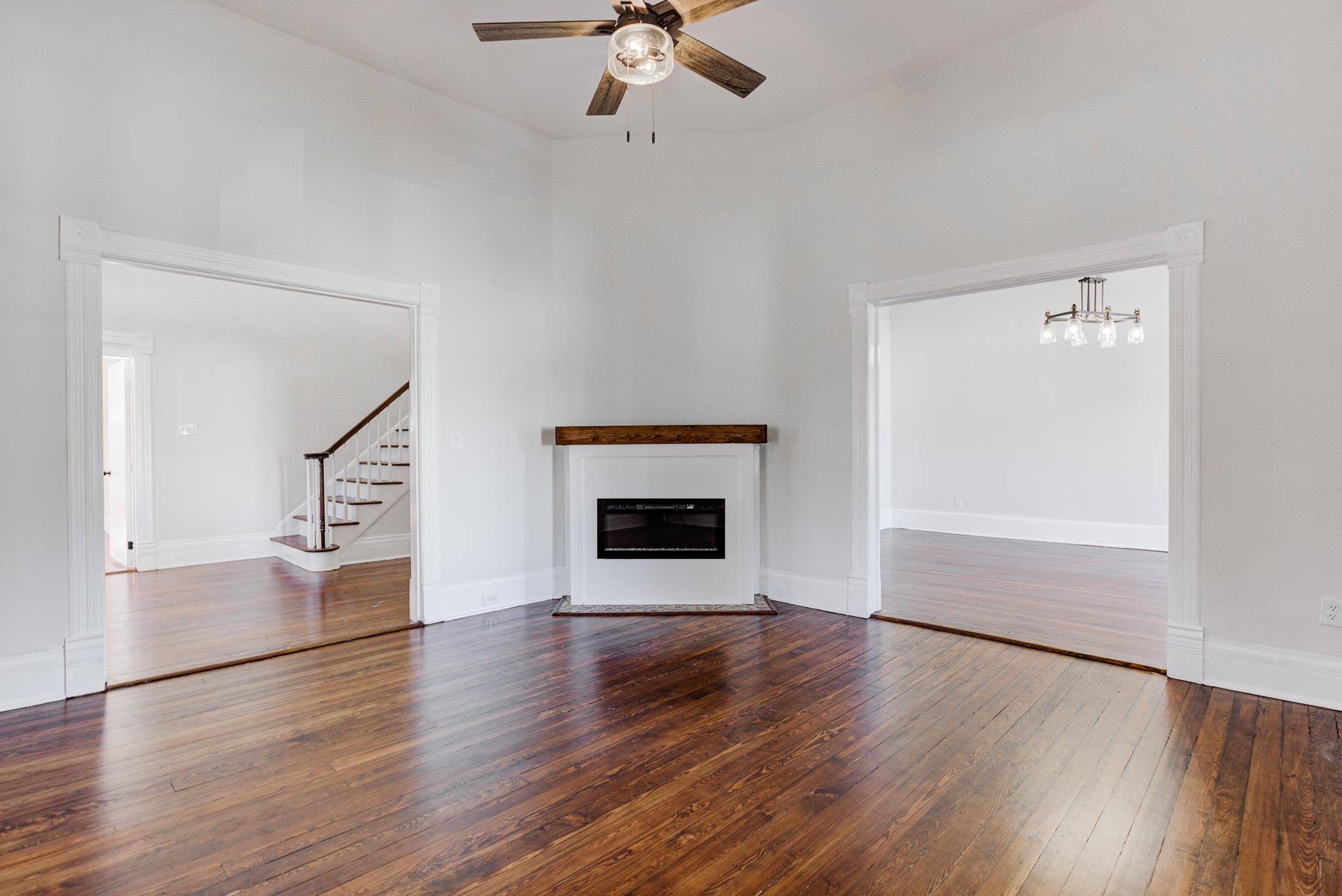 843 South Main Street Covington, TN 38019 - Photo 6 of 25 an empty room with wooden floor fireplace and windows