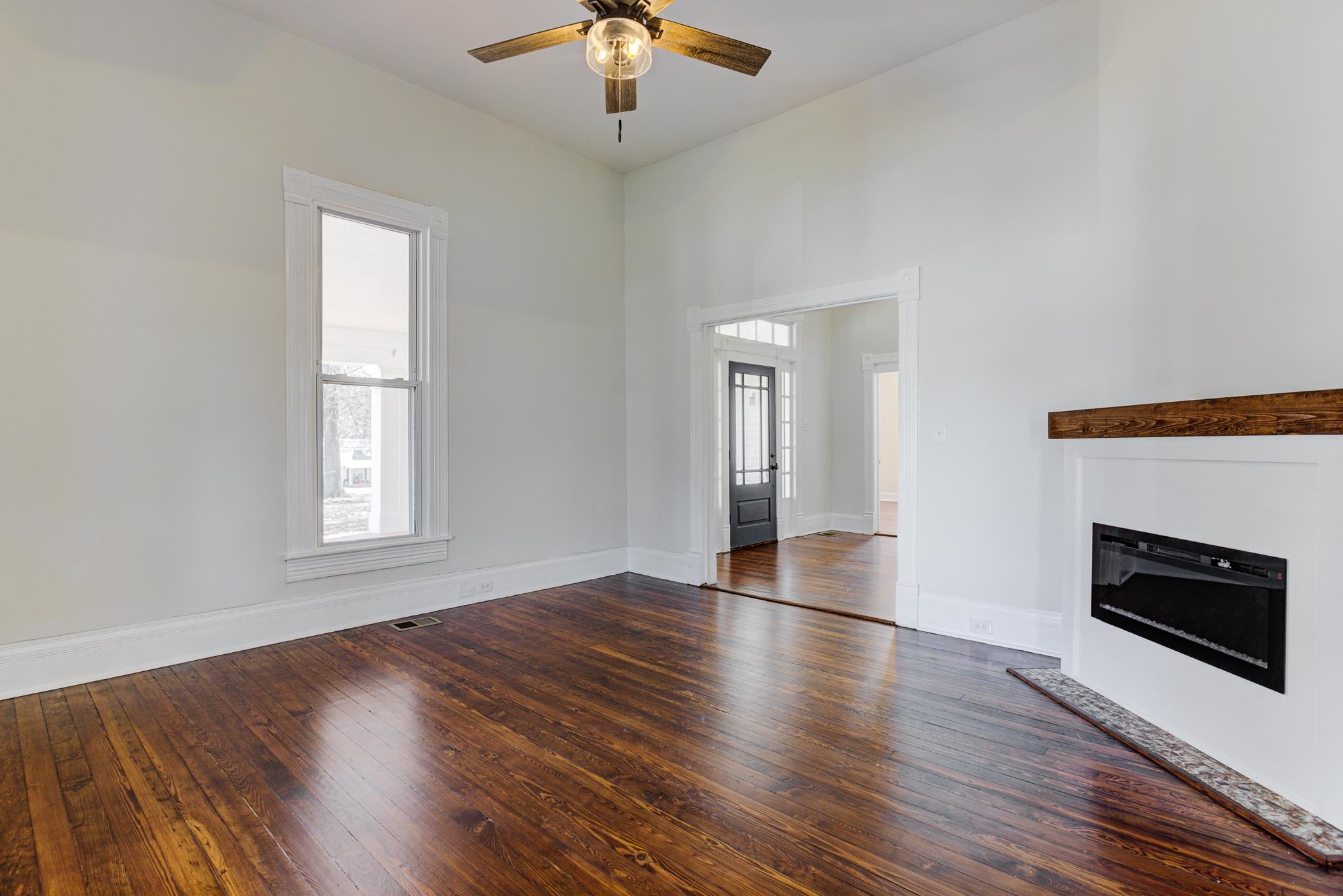 843 South Main Street Covington, TN 38019 - Photo 7 of 25 an empty room with wooden floor fireplace and windows