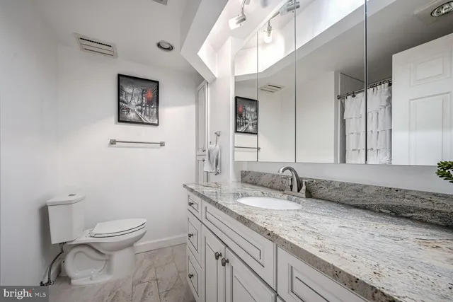 a bathroom with a granite countertop toilet sink and mirror