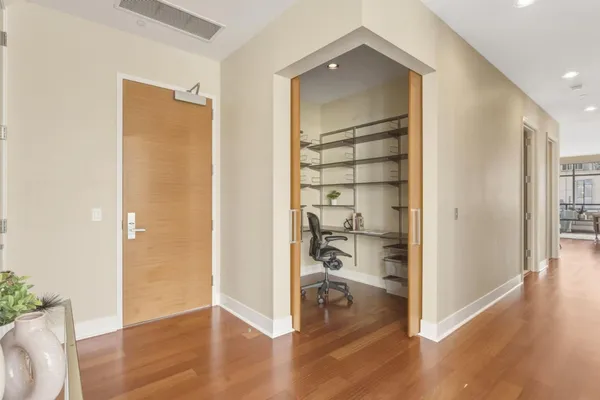 a view of a hallway with wooden floor and closet area