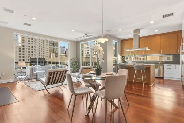 a view of a dining room and livingroom with furniture wooden floor a chandelier