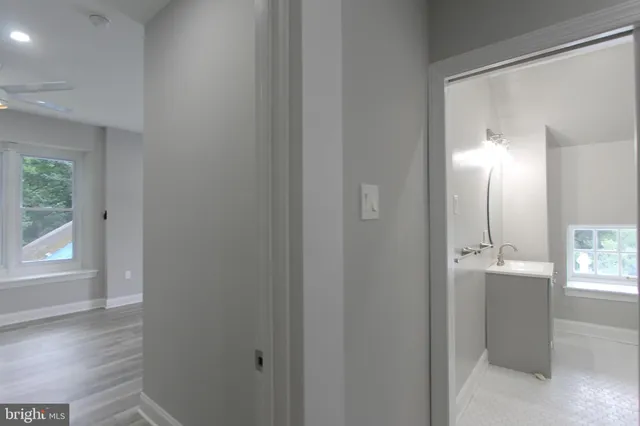 a view of a hallway with wooden floor and a bathroom
