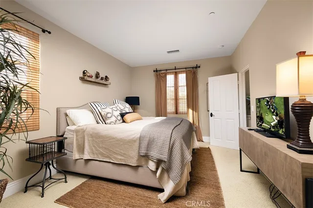 a spacious bedroom with a bed a couch and a flat tv screen on dresser