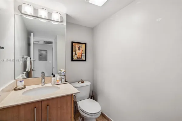 a bathroom with a granite countertop toilet sink mirror and vanity
