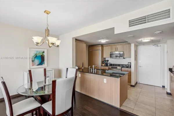 a dining room filled chandelier and kitchen view