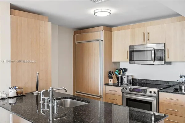 a kitchen with stainless steel appliances granite countertop a sink a stove and a refrigerator with wooden floor