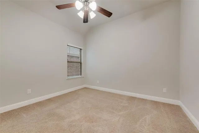 an empty room with a chandelier fan and windows