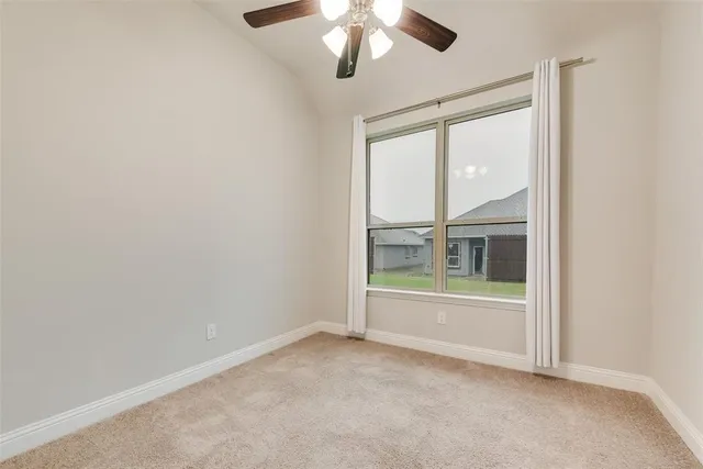 an empty room with ceiling fan and window
