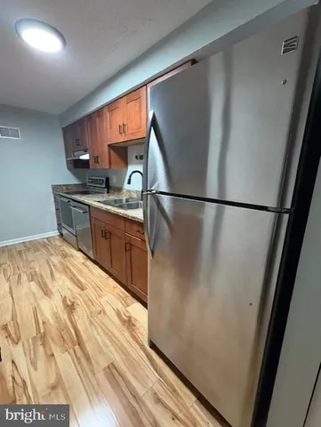 a kitchen with stainless steel appliances a refrigerator sink and wooden floor