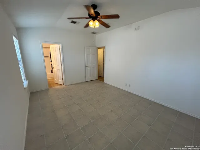en empty room with closet and a chandelier fan