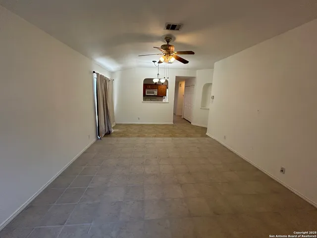 en empty room with windows and ceiling fan