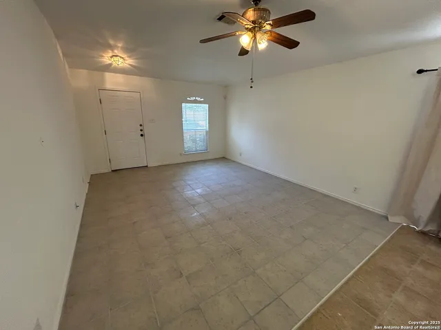 an empty room with windows and fan
