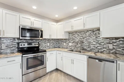 a kitchen with cabinets stainless steel appliances a sink and a stove