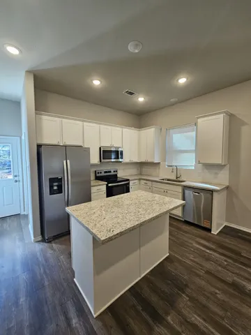 a large kitchen with kitchen island a sink a center island stainless steel appliances and a counter top space