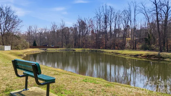 a view of a lake with chairs and wooden fence