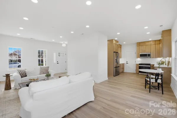 a living room with stainless steel appliances furniture and kitchen view