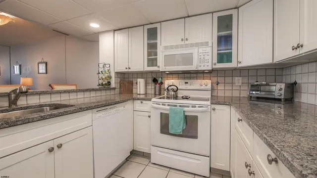 a kitchen with granite countertop white cabinets and white appliances