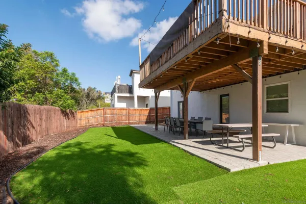 a view of a backyard with table and chairs potted plants and wooden fence