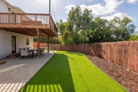 a view of a backyard with a patio and wooden fence