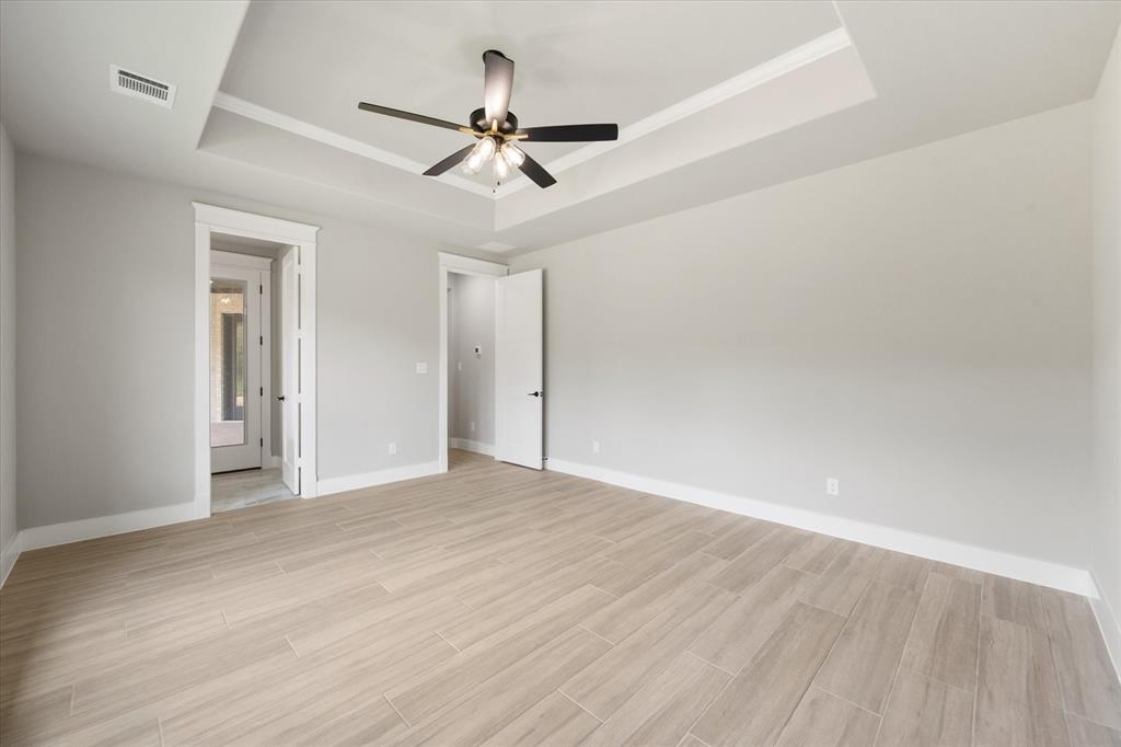 6610 Waggoner Way Midlothian, TX 76065 - Photo 30 of 40 Spacious interior featuring wood-look tile flooring, light gray walls, a tray ceiling with crown molding, and a modern ceiling fan