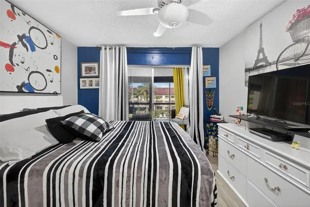 a bedroom with a bed and a flat tv screen on dresser next to a window