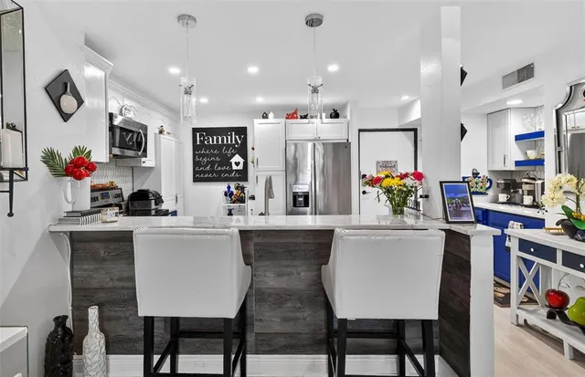 a kitchen with stainless steel appliances kitchen island granite countertop a dining table chairs and white cabinets