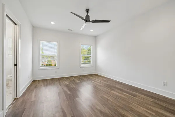 a view of a room with wooden floor a ceiling fan and window