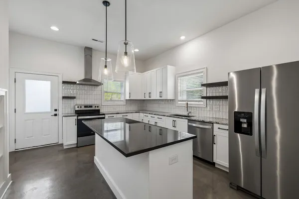 a kitchen with stainless steel appliances granite countertop a sink stove and refrigerator