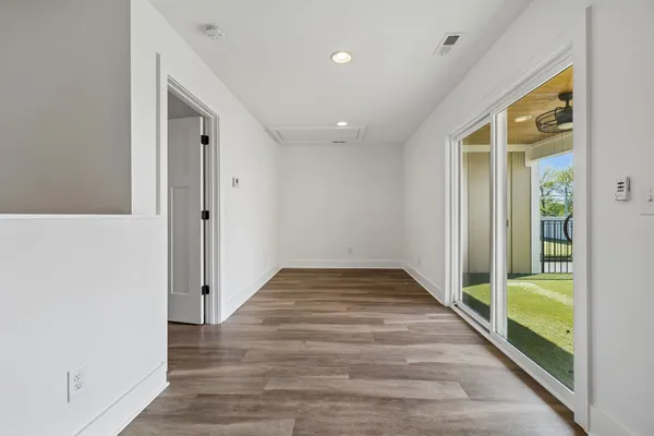 an empty room with wooden floor a ceiling fan and windows