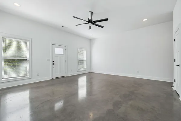 a view of an empty room with a window and a kitchen
