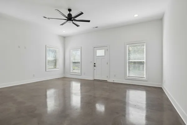 an empty room with wooden floor closet and windows
