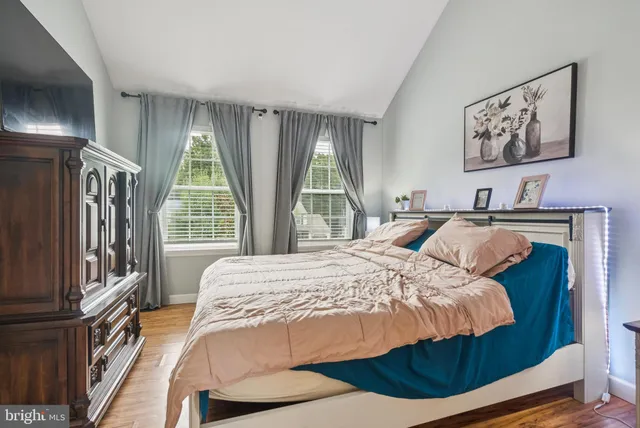 a bedroom with a bed painting on wall and a large window